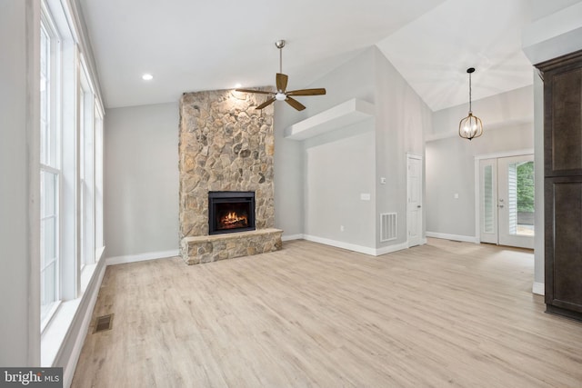 unfurnished living room featuring ceiling fan, a stone fireplace, light wood-type flooring, and lofted ceiling