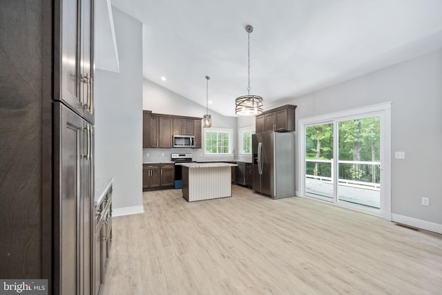 kitchen with dark brown cabinetry, pendant lighting, lofted ceiling, stainless steel appliances, and a center island