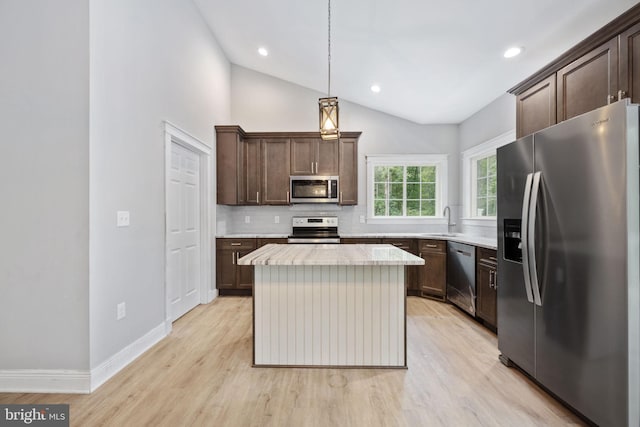 kitchen featuring pendant lighting, stainless steel appliances, lofted ceiling, a center island, and sink