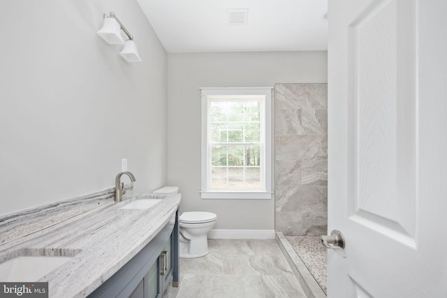 bathroom with tiled shower, vanity, and toilet