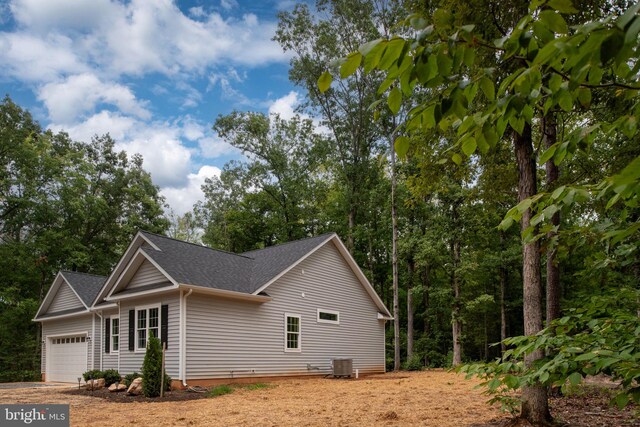 view of side of home featuring cooling unit and a garage