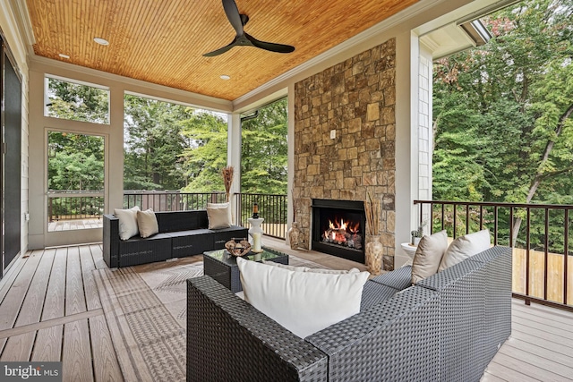 sunroom / solarium featuring an outdoor stone fireplace, wooden ceiling, and a ceiling fan