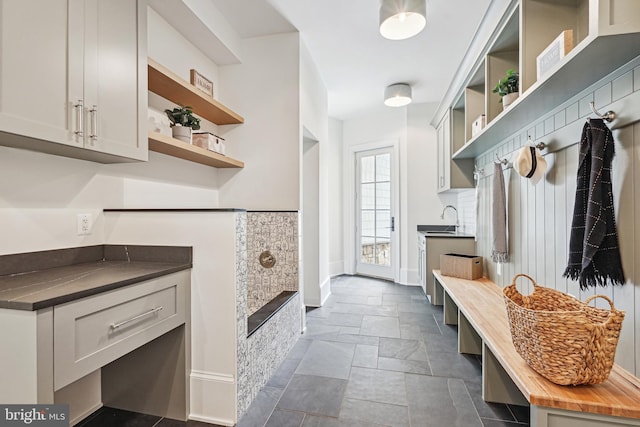 mudroom featuring a sink, stone tile flooring, and baseboards