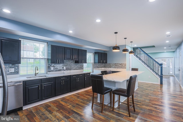 kitchen featuring a kitchen island, sink, a kitchen breakfast bar, hanging light fixtures, and stainless steel dishwasher