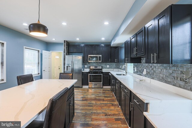 kitchen featuring tasteful backsplash, stainless steel appliances, light stone countertops, dark hardwood / wood-style floors, and decorative light fixtures