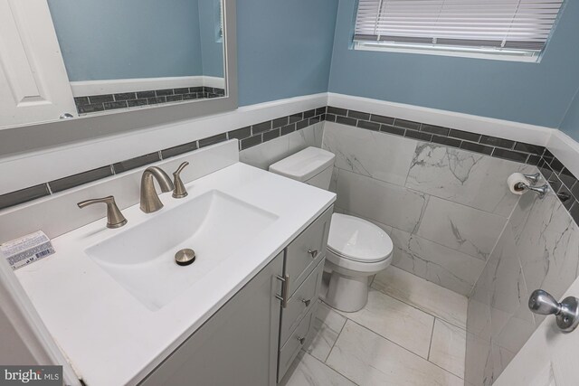 bathroom featuring tile patterned floors, tile walls, vanity, and toilet