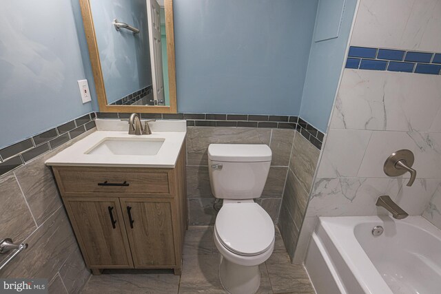 bathroom featuring tile patterned floors, vanity, tile walls, and toilet