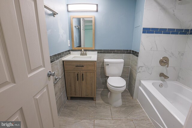 full bathroom with tile walls, washtub / shower combination, toilet, tile patterned floors, and vanity