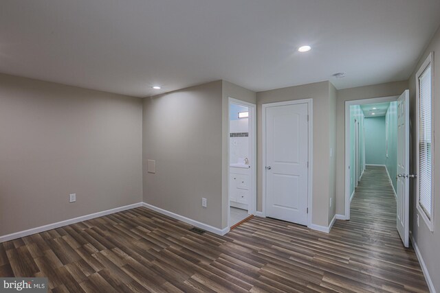 unfurnished bedroom with connected bathroom and dark hardwood / wood-style floors