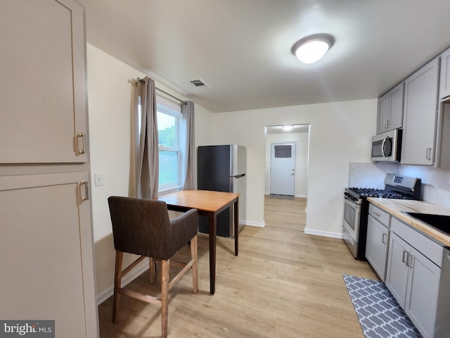 kitchen featuring sink, light wood-type flooring, stainless steel appliances, and gray cabinets