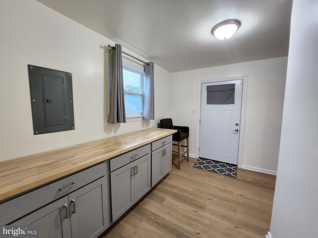 kitchen with butcher block counters, electric panel, gray cabinets, and light hardwood / wood-style floors