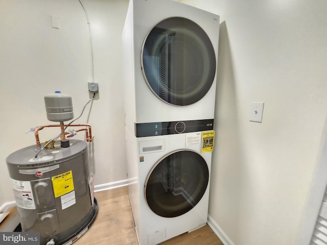 laundry area with electric water heater, stacked washer / drying machine, and light wood-type flooring