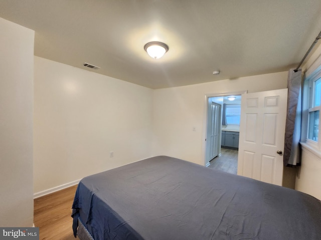 bedroom featuring connected bathroom and hardwood / wood-style floors