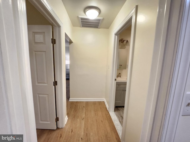 hallway with sink and light wood-type flooring