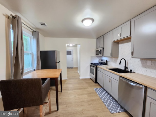 kitchen featuring gray cabinets, appliances with stainless steel finishes, light hardwood / wood-style flooring, and sink