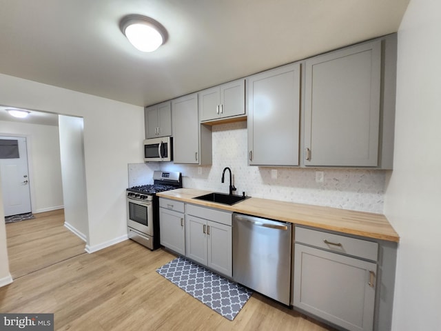 kitchen with wooden counters, stainless steel appliances, light wood-type flooring, and sink