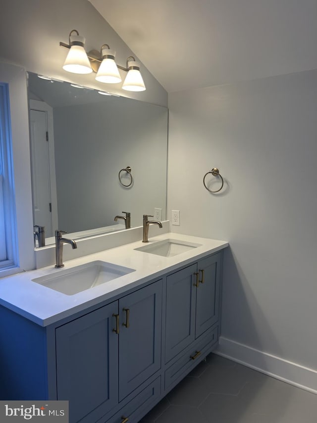 full bathroom featuring double vanity, baseboards, tile patterned floors, and a sink