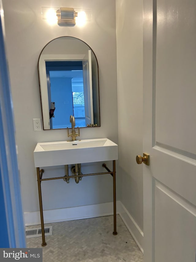 bathroom featuring baseboards, visible vents, and a sink