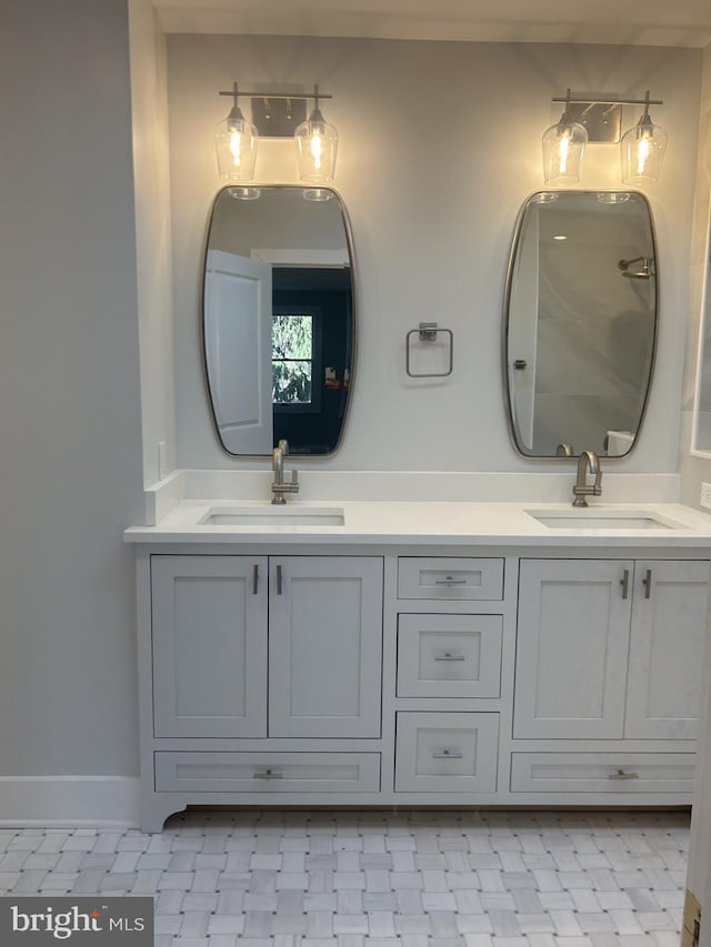 full bath with a sink, baseboards, and double vanity