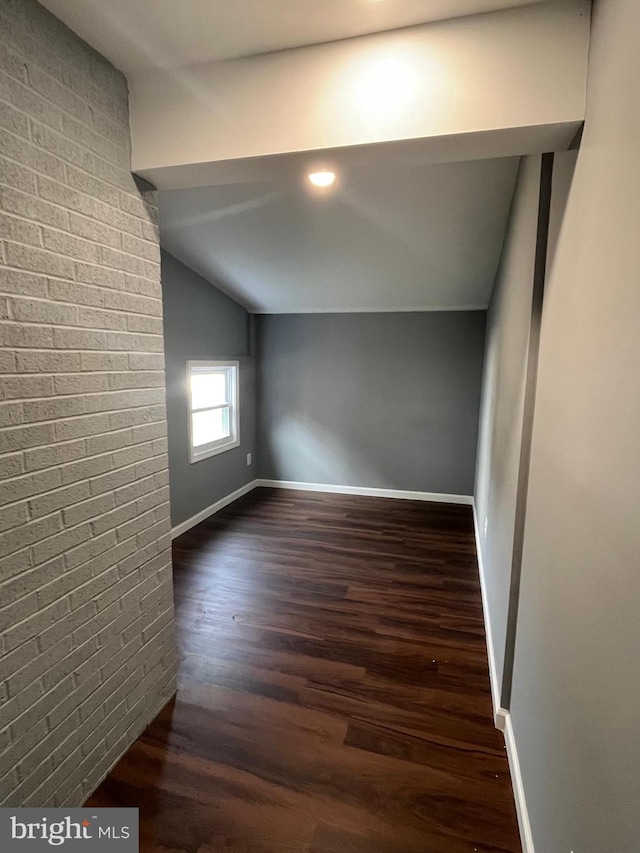 bonus room with brick wall, vaulted ceiling, and hardwood / wood-style floors