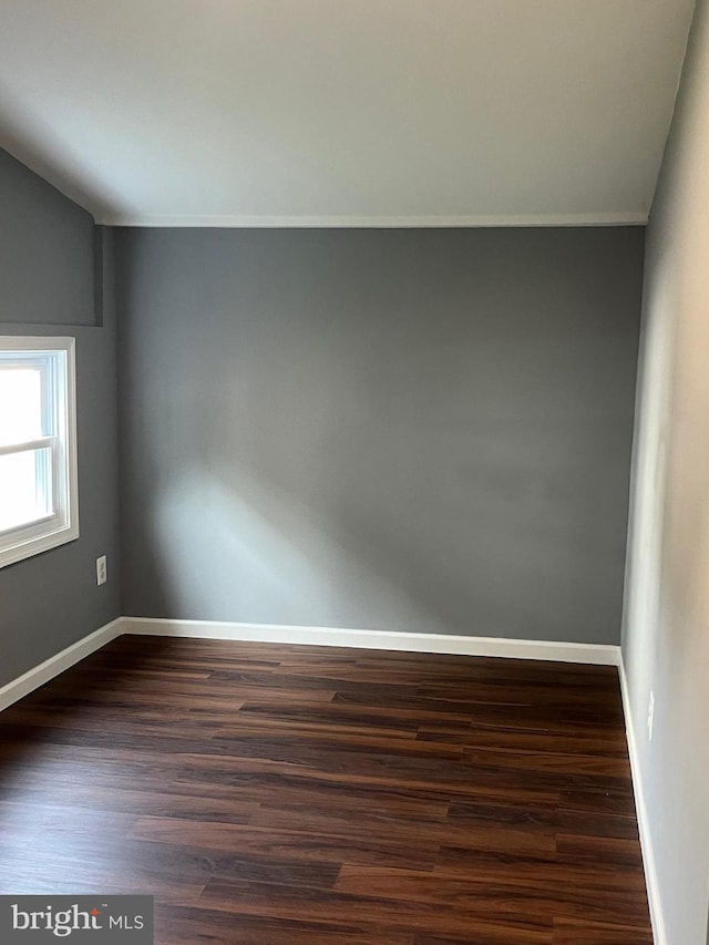 spare room featuring vaulted ceiling and hardwood / wood-style floors