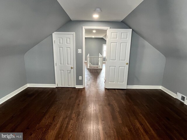 additional living space featuring dark wood-type flooring and lofted ceiling