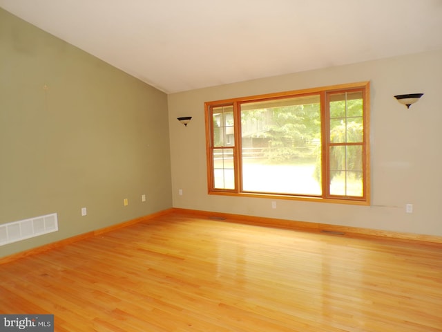 empty room with lofted ceiling and light hardwood / wood-style flooring