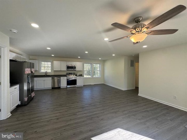 unfurnished living room featuring a wealth of natural light and dark wood-type flooring