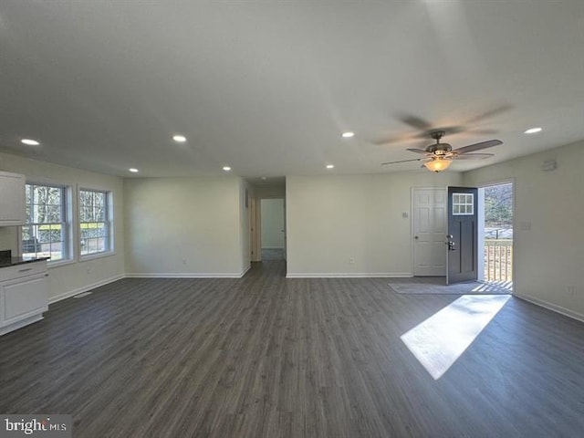 unfurnished living room featuring dark wood-type flooring, ceiling fan, and a wealth of natural light