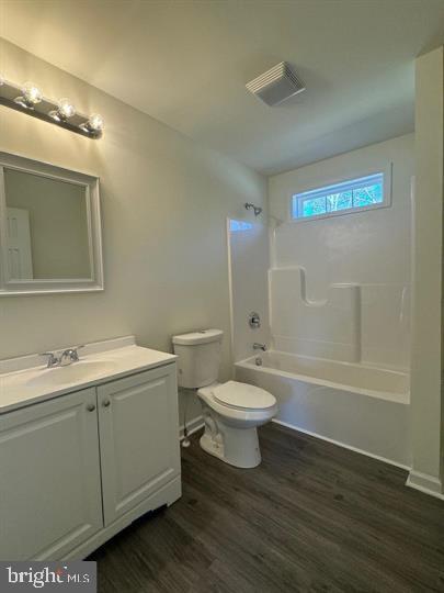 full bathroom with vanity, wood-type flooring, shower / bathtub combination, and toilet