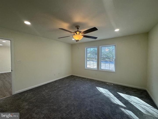 spare room with dark carpet and ceiling fan