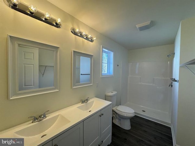 bathroom with wood-type flooring, walk in shower, vanity, and toilet