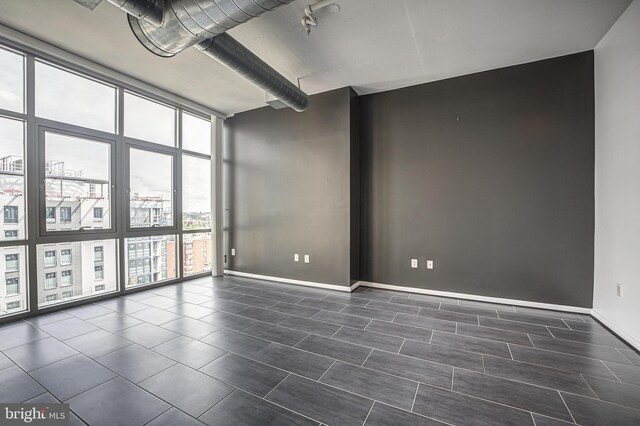 tiled empty room featuring floor to ceiling windows