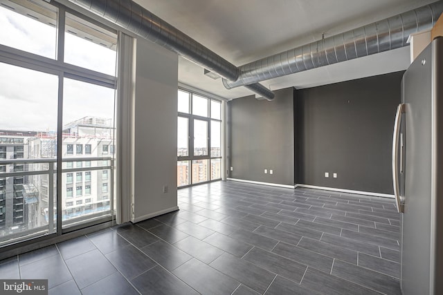 spare room with expansive windows and dark tile patterned floors