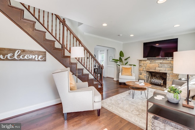 living room with hardwood / wood-style flooring, ornamental molding, and a fireplace