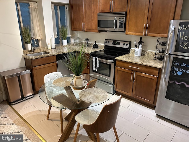 kitchen with light stone counters, light tile patterned floors, stainless steel appliances, and sink