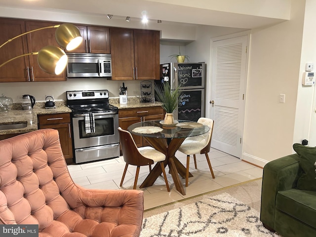 kitchen featuring light stone counters, light tile patterned flooring, sink, dark brown cabinets, and stainless steel appliances