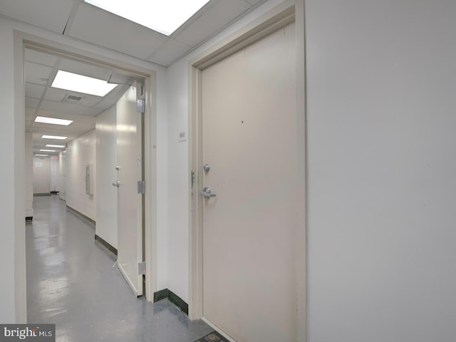 hall with concrete flooring and a paneled ceiling