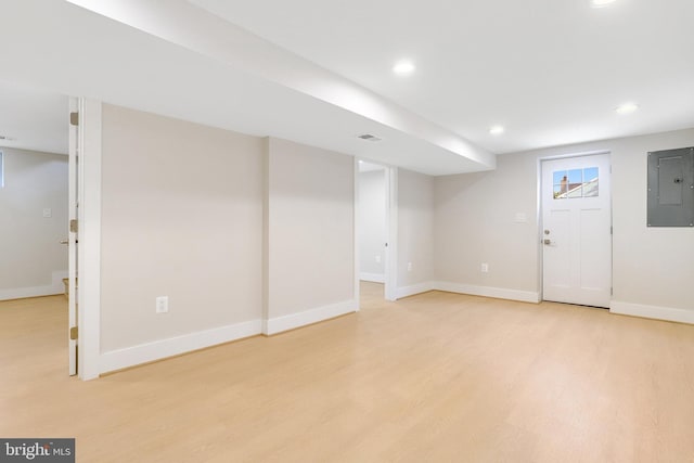 basement featuring light hardwood / wood-style flooring and electric panel