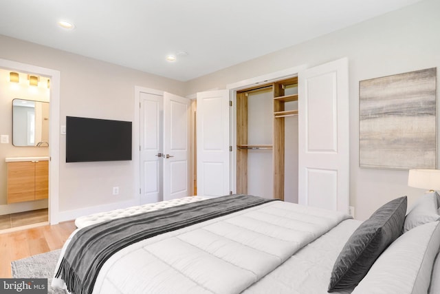 bedroom featuring ensuite bathroom, light wood-type flooring, and a closet