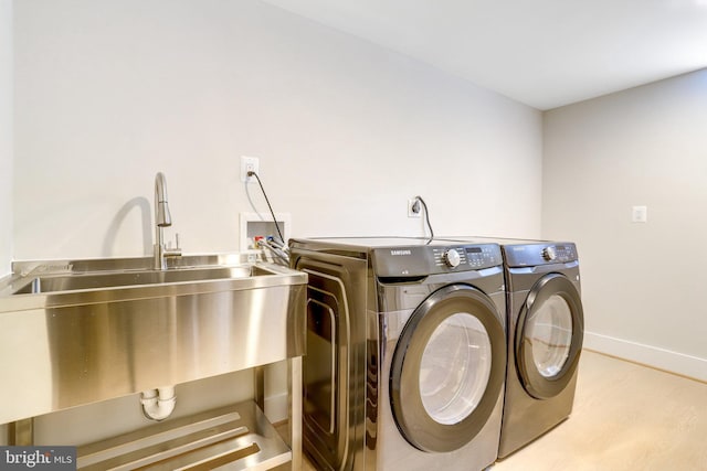 clothes washing area with sink, independent washer and dryer, and light hardwood / wood-style floors