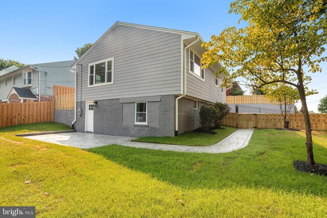 back of house with a patio and a lawn