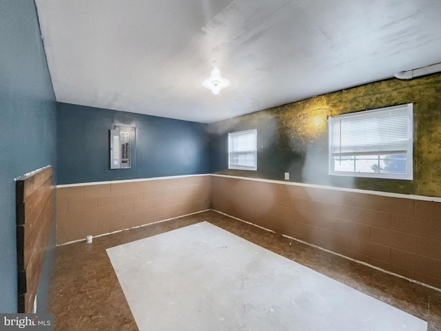 empty room featuring electric panel, tile walls, and plenty of natural light