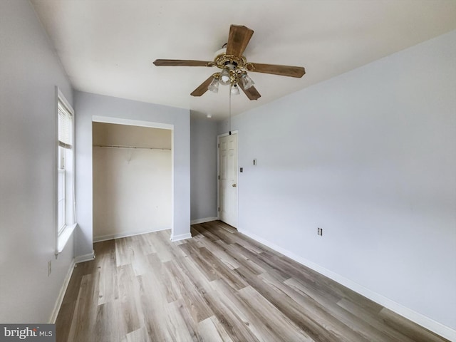 unfurnished bedroom featuring multiple windows, light wood-type flooring, ceiling fan, and a closet