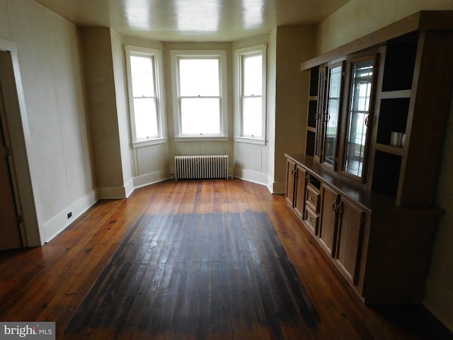 unfurnished dining area featuring radiator heating unit and wood-type flooring