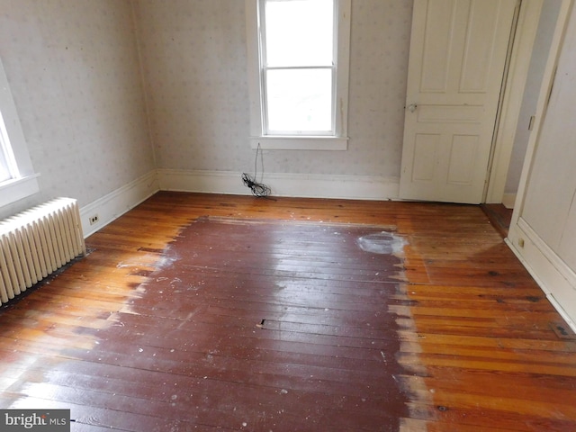 empty room featuring radiator heating unit and hardwood / wood-style floors