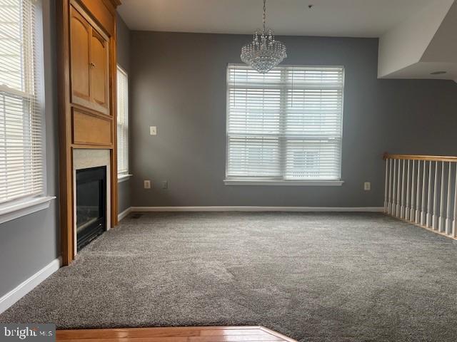 unfurnished living room featuring a chandelier and carpet flooring