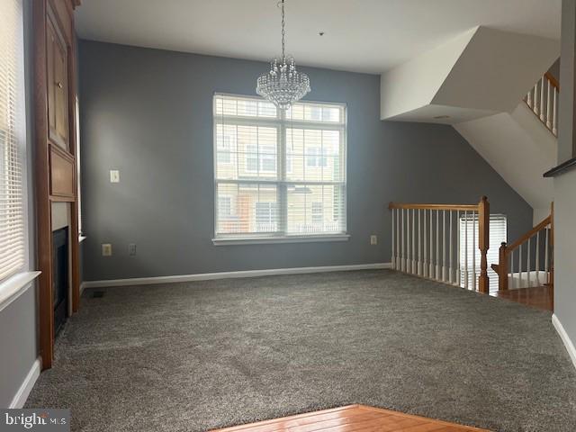 unfurnished dining area with lofted ceiling, a chandelier, and carpet floors