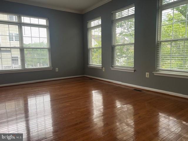 unfurnished room featuring a wealth of natural light, ornamental molding, and wood-type flooring