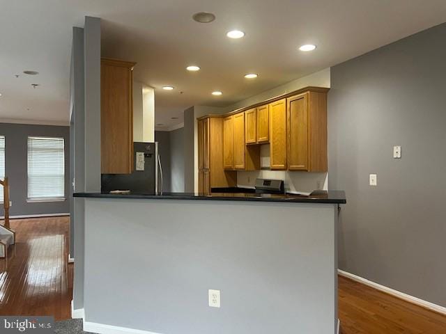 kitchen with kitchen peninsula, refrigerator, and dark hardwood / wood-style flooring